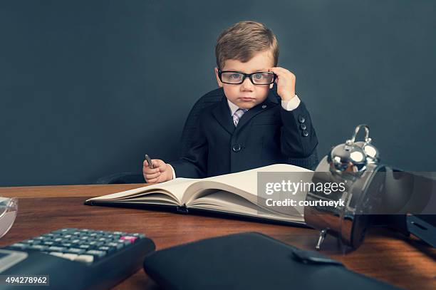 young boy vestirse en traje de trabajo en el escritorio. - bossy fotografías e imágenes de stock