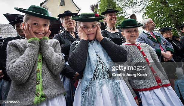 Young Pilgrims in traditional Bavarian folk costumes cover their ears as saluting guns fire during an outdoor mass to celebrate Ascension at the...