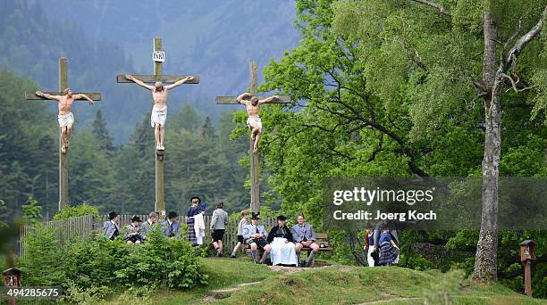 Pilgrims in traditional Bavarian folk costumes stand beneath three crosses on the Kalvarienberg-mountain and follow an outdoor mass to celebrate...