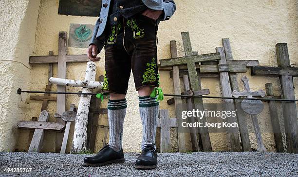 Pilgrim in a traditional Bavarian folk costume stands beside wooden pilgrim-crosses and attends an outdoor mass to celebrate Ascension at the...