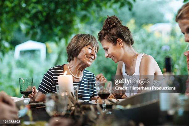 mother and daughter chatting during garden party - dochter stockfoto's en -beelden