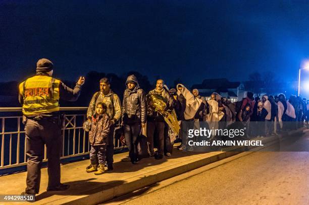 Policeman gestures as refugees wait in line on the Innbruecke bridge at the German/Austrian border at Simbach am Inn, southern Germany on October 25,...