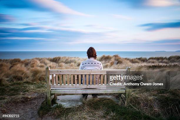 man sitting on bench overlooking the sea - loneliness stock pictures, royalty-free photos & images