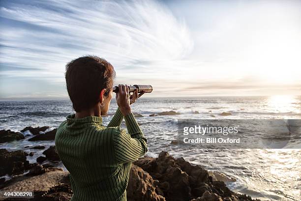 woman with spyglass looking toward ocean - hand held telescope stock pictures, royalty-free photos & images