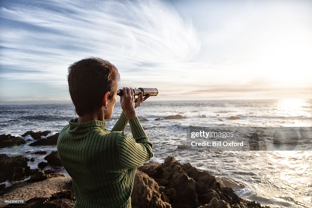 Mulher com uma luneta olhando para o mar