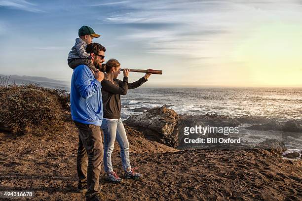 family with spyglass looking toward ocean - day telescope stock pictures, royalty-free photos & images