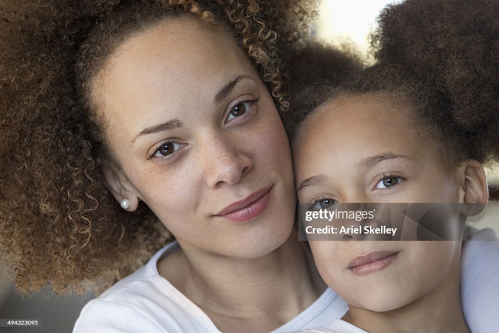 Black mother hugging daughter