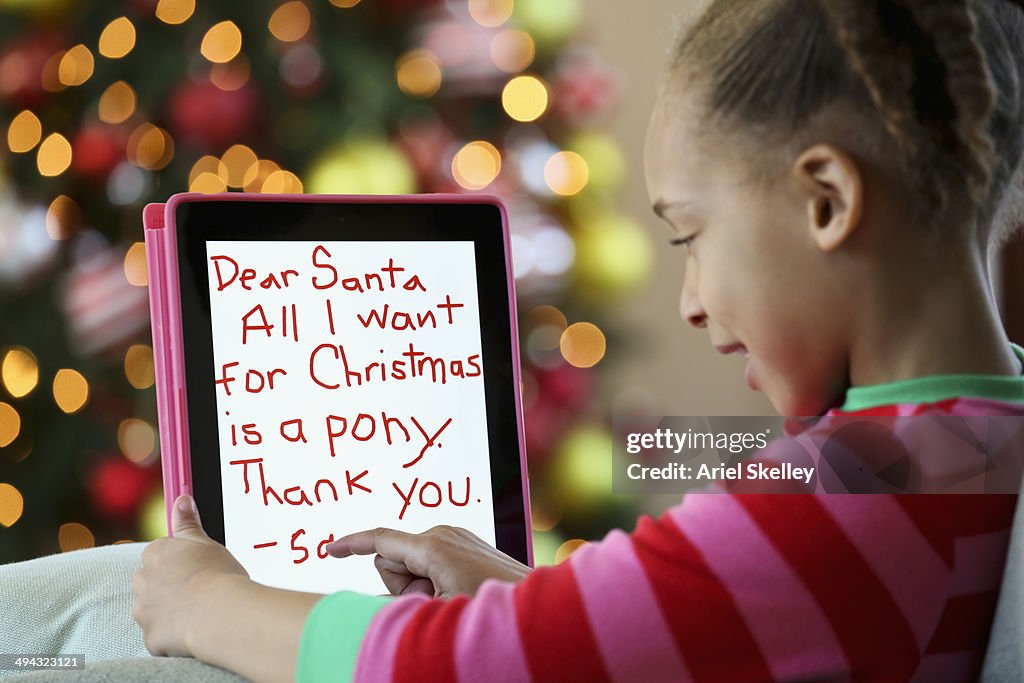 Black girl writing letter to Santa on digital tablet