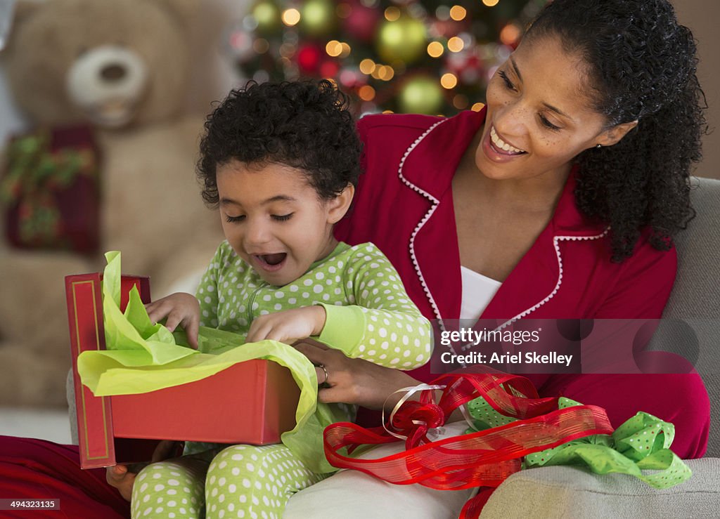 Mixed race mother and daughter opening Christmas present
