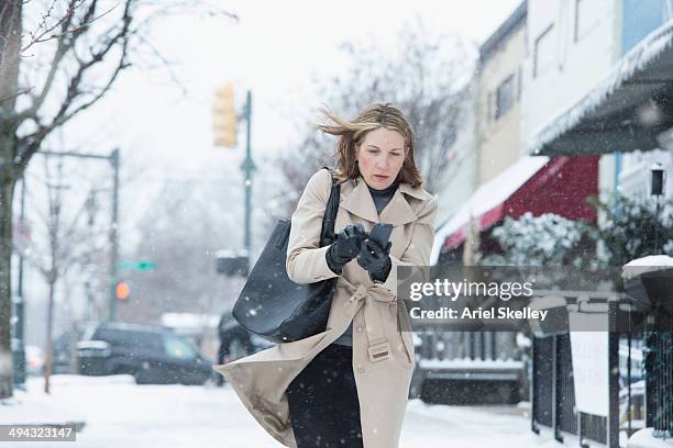 woman walking on snowy street - freeze motion stock-fotos und bilder