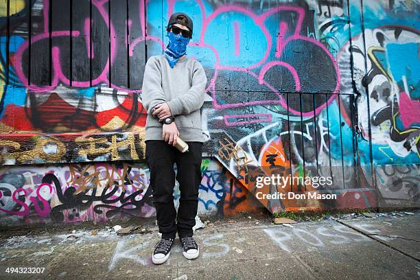 caucasian teenage boy standing by graffiti wall - graffiti artists stock-fotos und bilder