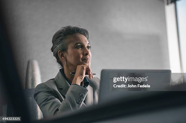 mixed race businesswoman using laptop in office - grey hair stress stock pictures, royalty-free photos & images