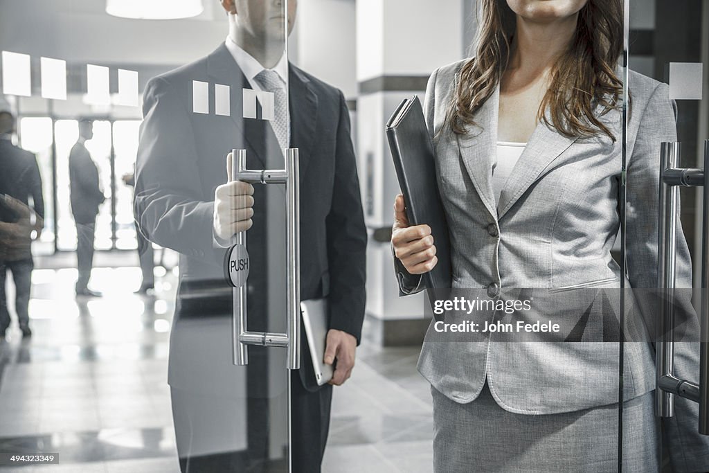 Businessman holding door open for female colleague