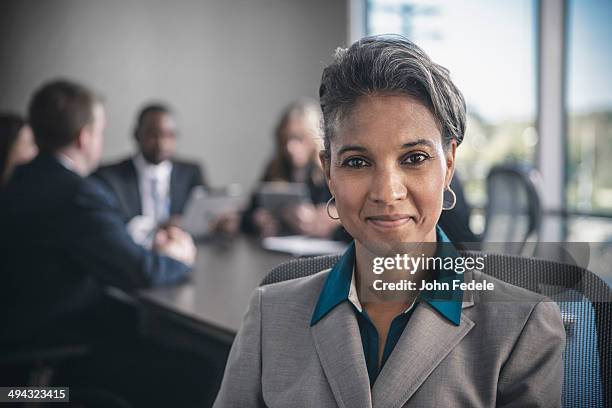 businesswoman smiling in conference room - black suit close up stock pictures, royalty-free photos & images