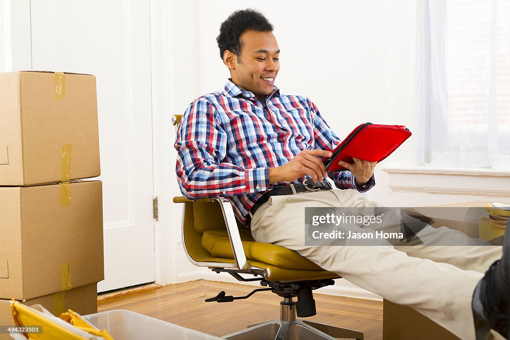 Mixed race man using digital tablet in new home