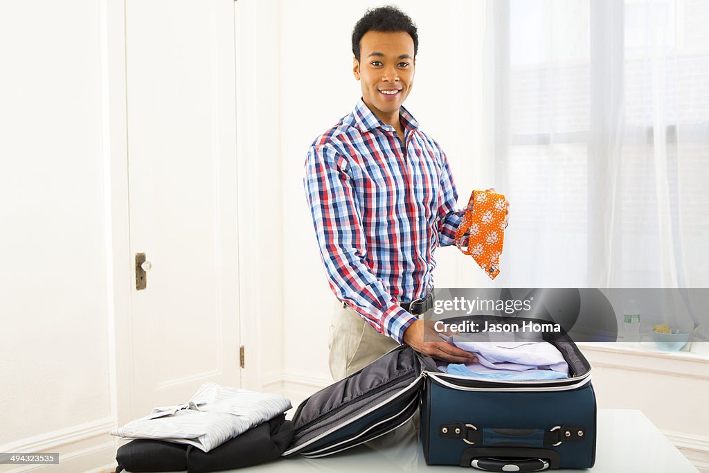 Mixed race businessman packing suitcase