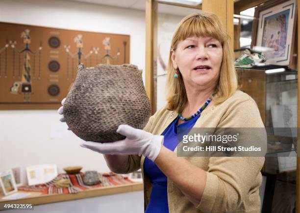 caucasian curator holding artifact in museum - museumswärter stock-fotos und bilder