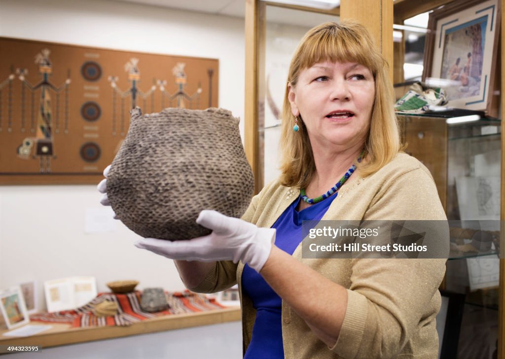 Caucasian curator holding artifact in museum