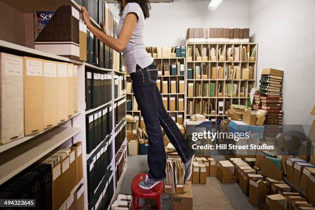 mixed race student working in archive - searching mess stock-fotos und bilder