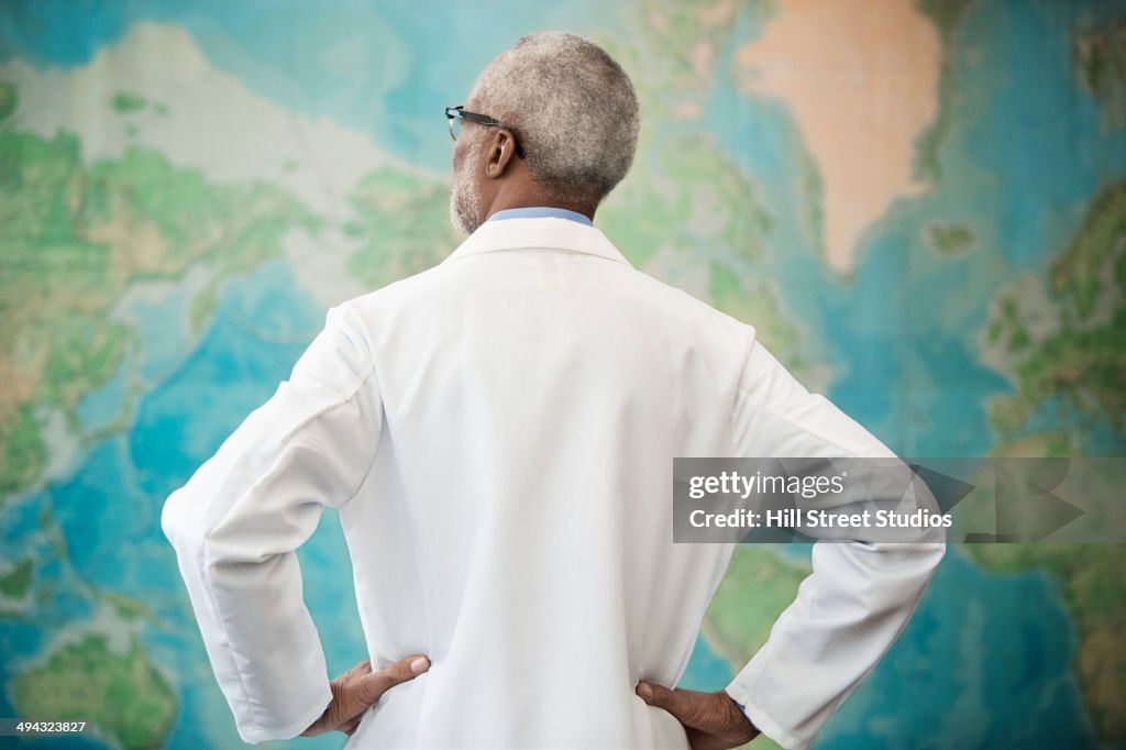 Black doctor examining world map in office