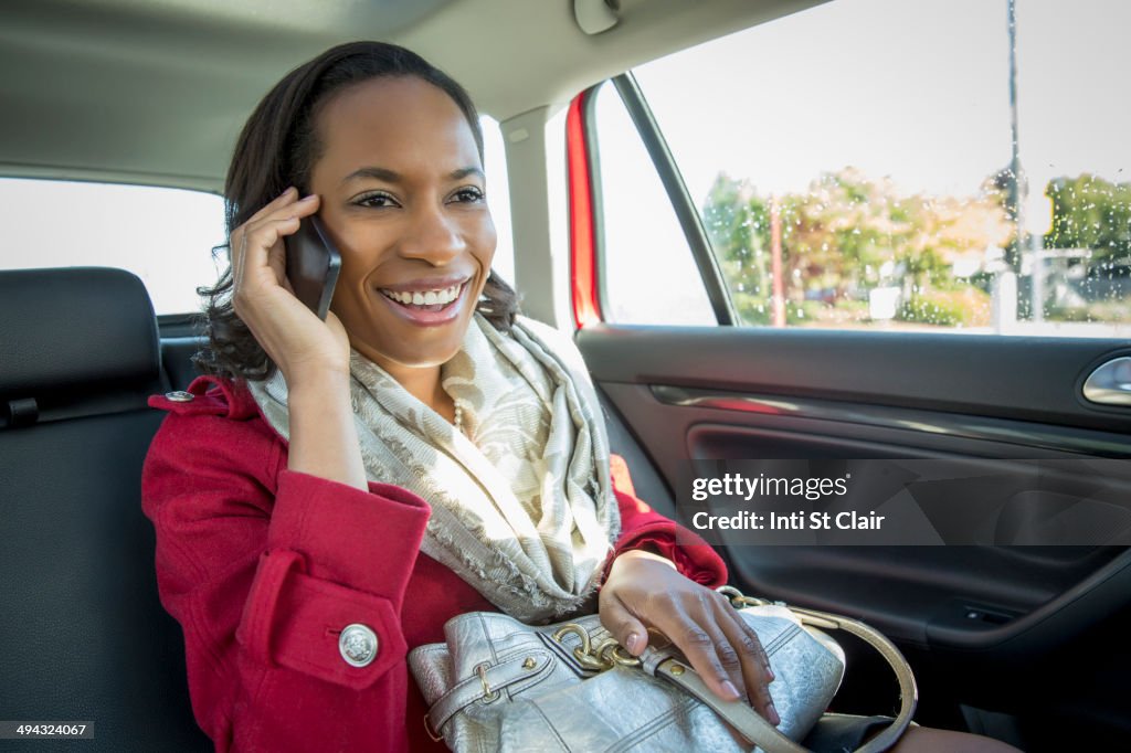 Black woman talking on cell phone in taxi