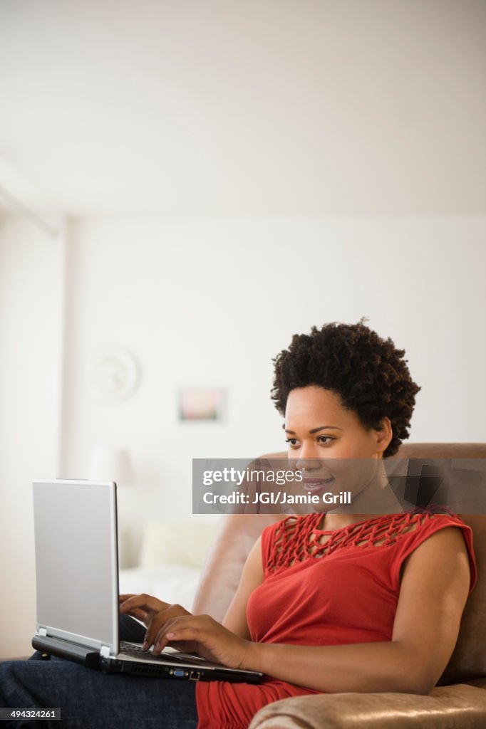 Black woman using laptop in armchair