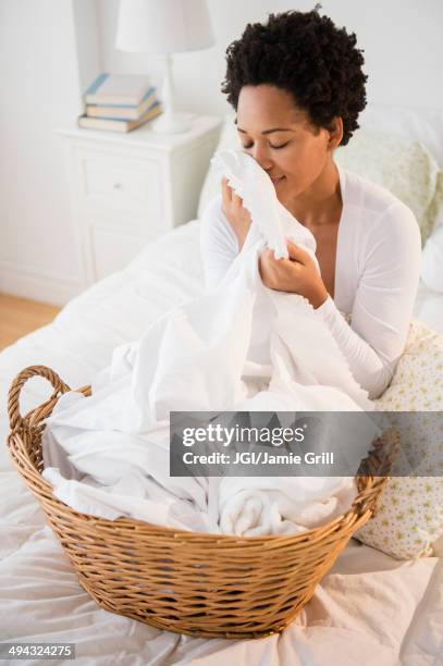 black woman smelling fresh laundry on bed - sábana ropa de cama fotografías e imágenes de stock