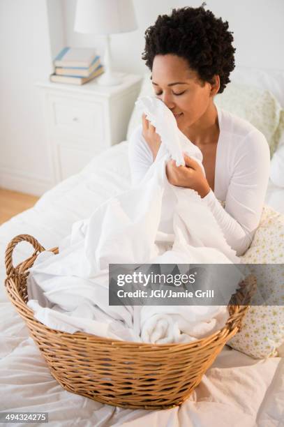 black woman smelling fresh laundry on bed - sheet bedding photos et images de collection