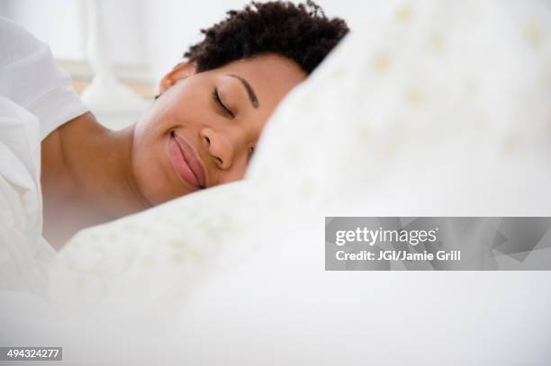 serene black woman laying in bed - female sleeping stock pictures, royalty-free photos & images