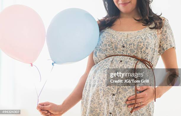 pregnant hispanic woman carrying balloon - babyshower stock-fotos und bilder