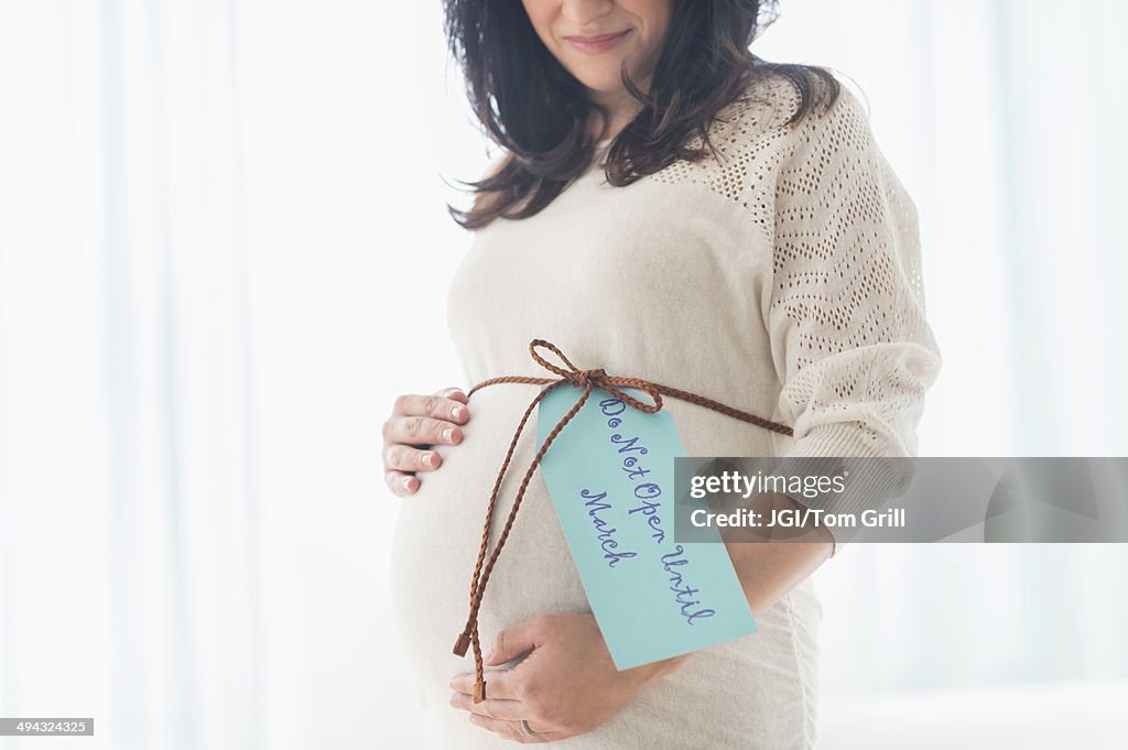 Pregnant Hispanic woman with gift wrap around belly