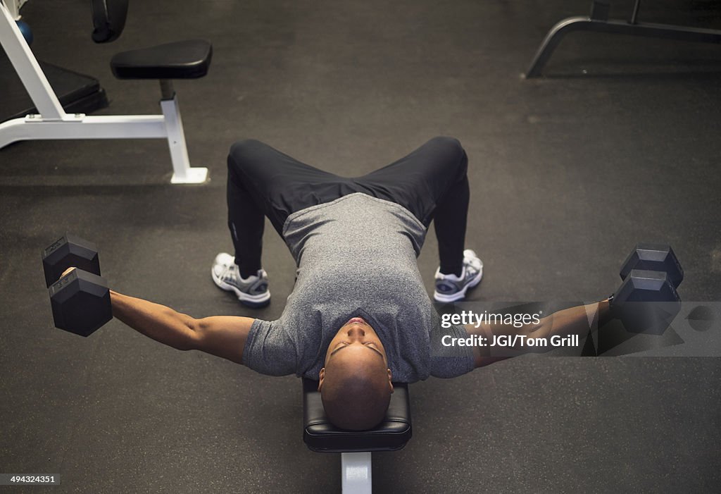 Black man lifting weights in gym