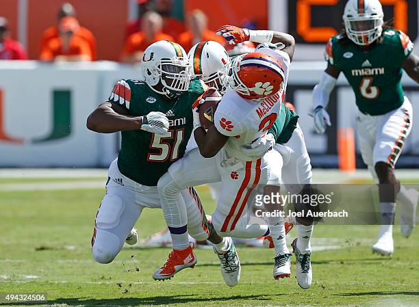 Ray-Ray McCloud of the Clemson Tigers is tackled by Juwon Young and Corn Elder of the Miami Hurricanes during first quarter action on October 24,...