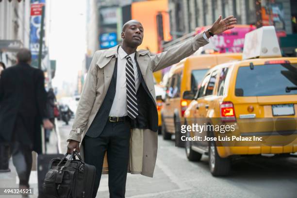 black businessman hailing taxi on city street - hail foto e immagini stock