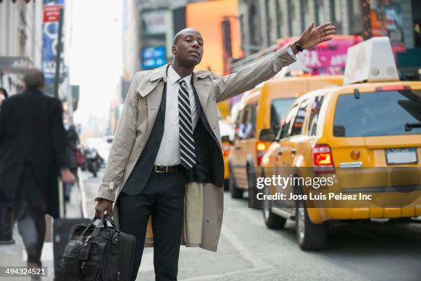 black businessman hailing taxi on city street - hail stock pictures, royalty-free photos & images