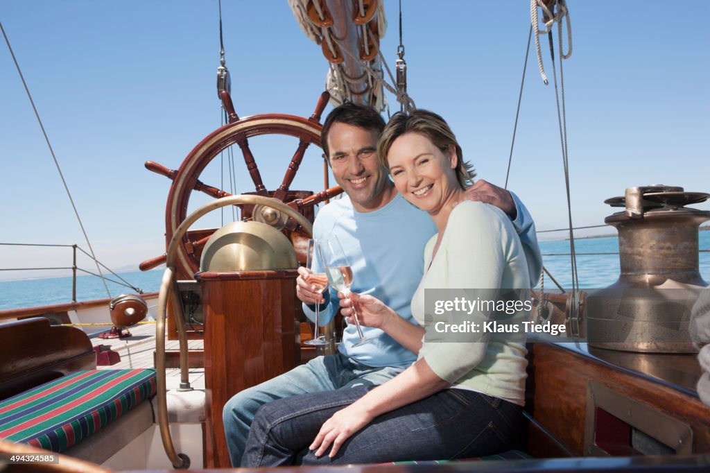 Caucasian couple toasting each other on sailboat