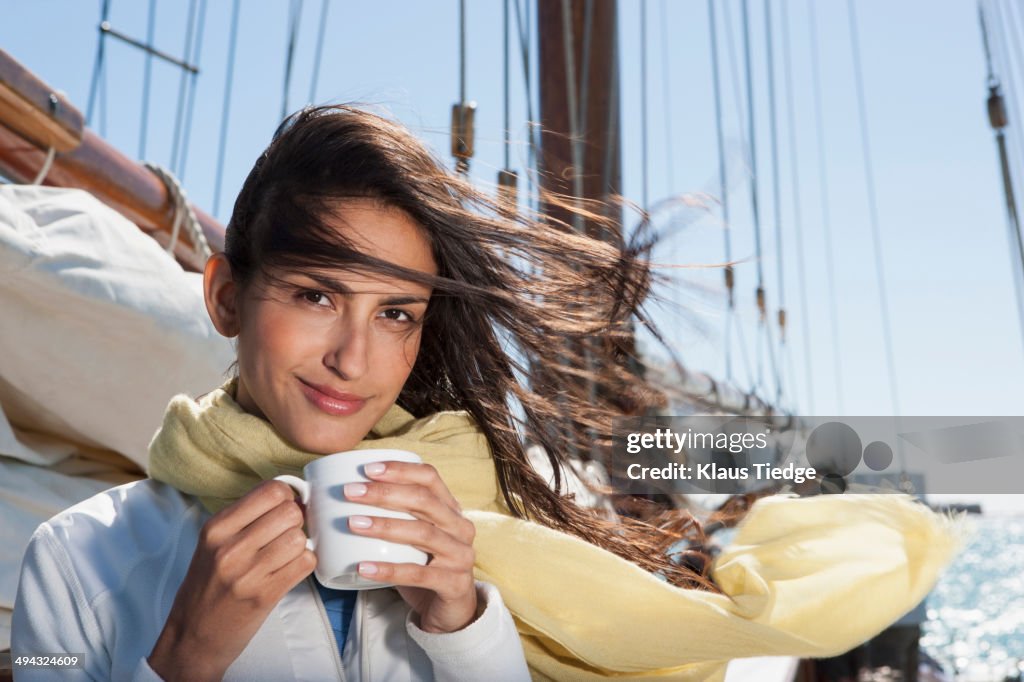 Caucasian woman drinking coffee on sailboat