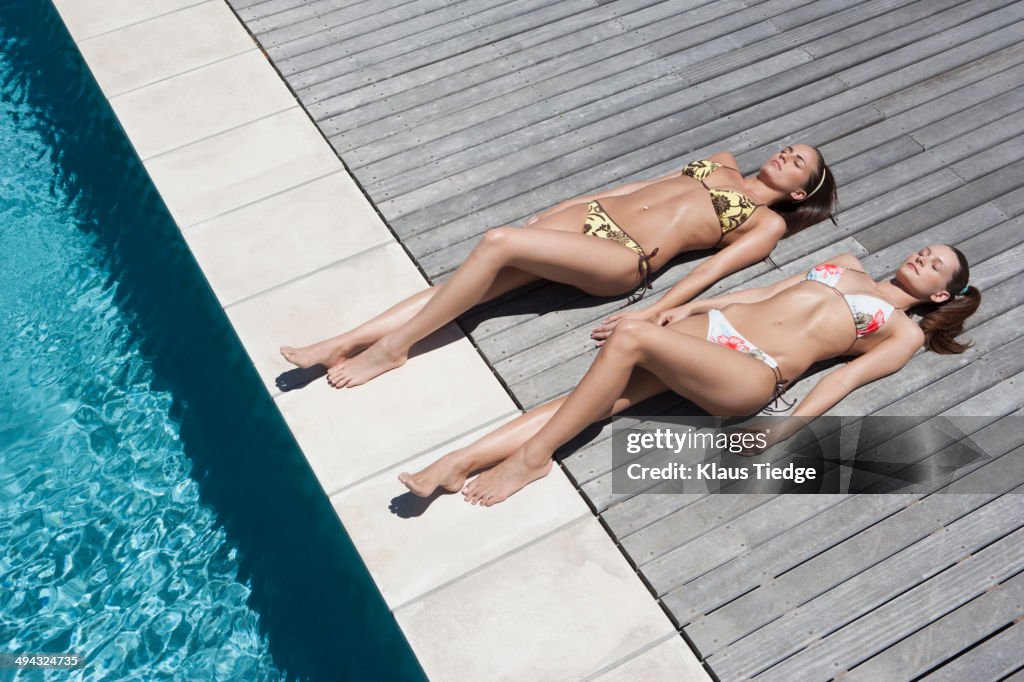 Caucasian women sunbathing by swimming pool