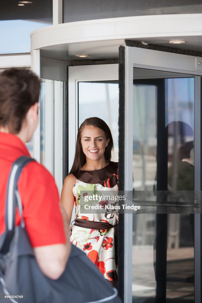 Caucasian couple greeting at revolving door