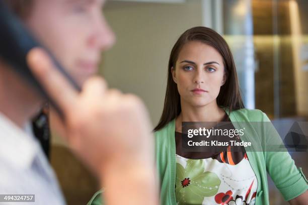 caucasian woman watching boyfriend talk on cell phone - girlfriend stock pictures, royalty-free photos & images