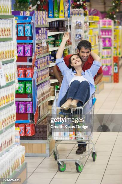 caucasian couple playing in grocery store - man pushing cart fun play stock pictures, royalty-free photos & images