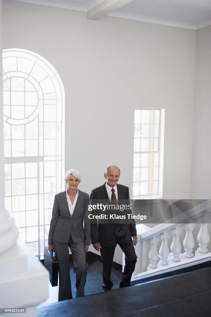 Senior Caucasian business people climbing office steps