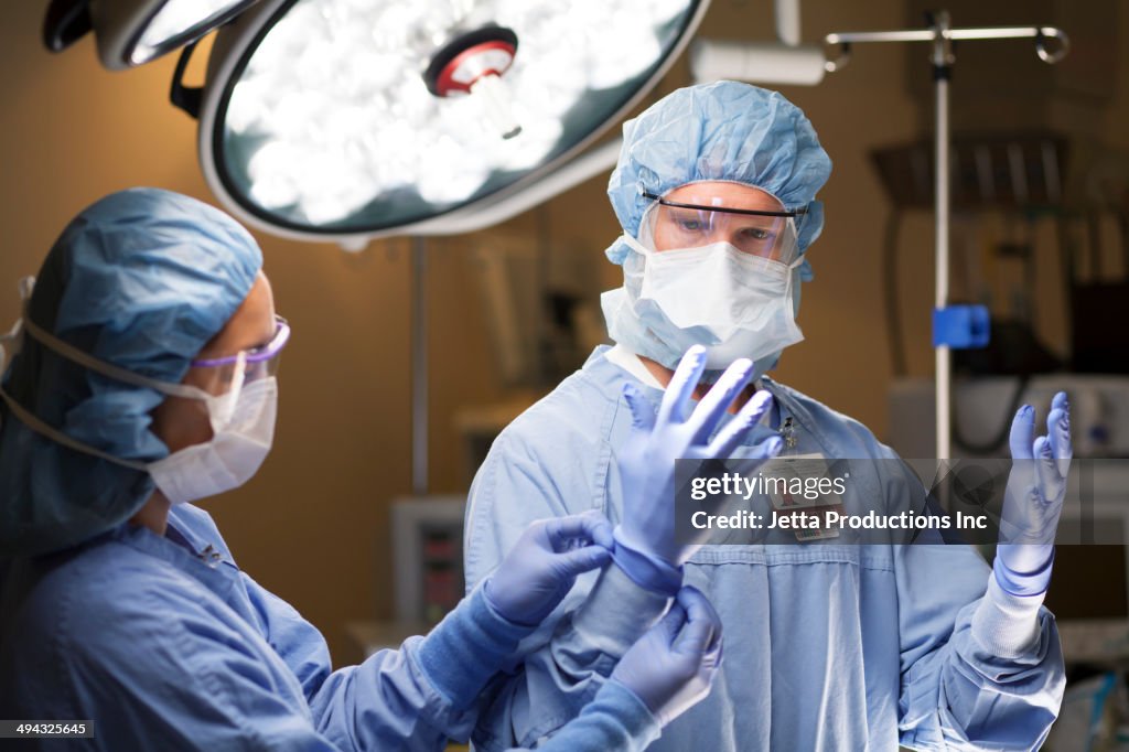 Nurse adjusting surgeon's gloves in operating room