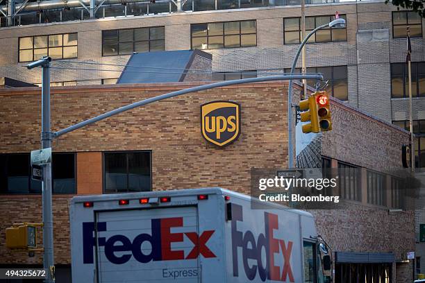 FedEx Corp. Truck passes a United Parcel Service Inc. Facility in New York, U.S., on Friday, Oct. 23, 2015. UPS is scheduled to release third-quarter...