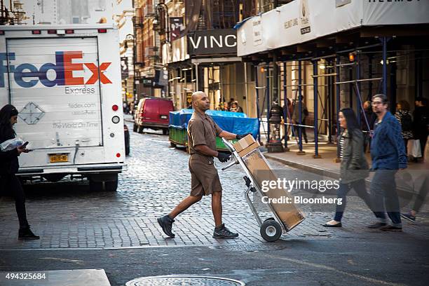 United Parcel Service Inc. Driverwalks past a FedEx Corp. Truck, left, while making a delivery in New York, U.S., on Friday, Oct. 23, 2015. UPS is...
