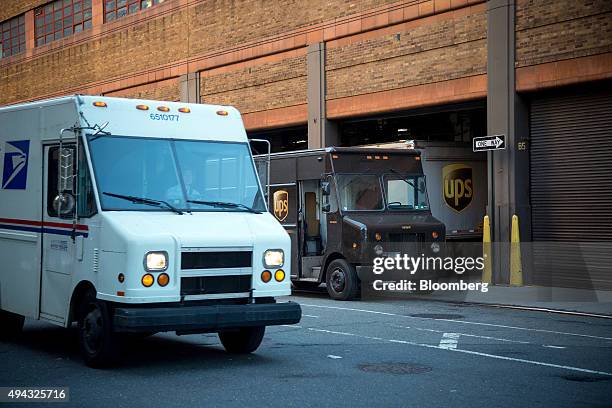 Postal Service vehicle drives past trucks parked at a United Parcel Service Inc. Facility in New York, U.S., on Friday, Oct. 23, 2015. UPS is...