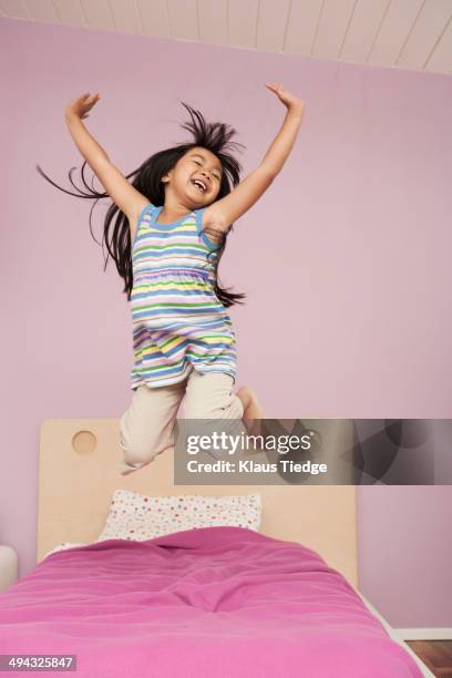 chinese girl jumping on bed - children jumping bed stock-fotos und bilder