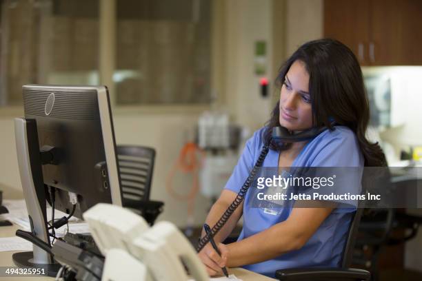 mixed race nurse taking notes in hospital - multitasking nurse stock pictures, royalty-free photos & images