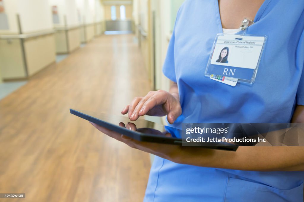 Mixed race nurse using digital tablet