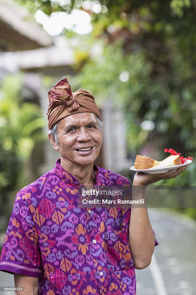 Balinese server carrying plate of food